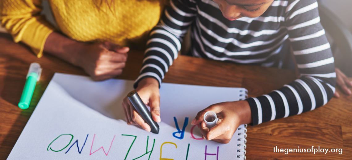 overhead view of parent helping child learn how to write the alphabet