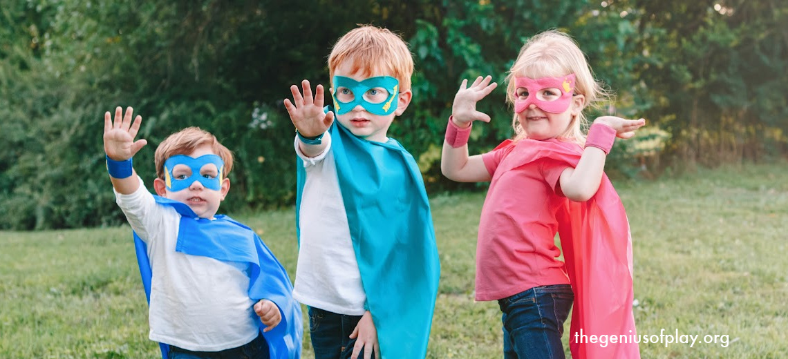 three preschool kids dressed up in superhero costumes playing pretend outdoors