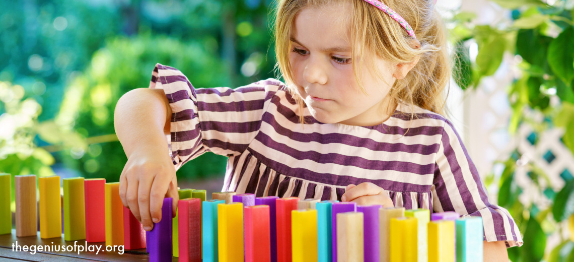 young preschool girl playing with colorful building blocks