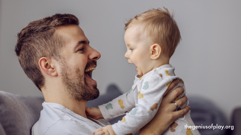 adorable baby boy smiling while being held up in his father’s arms