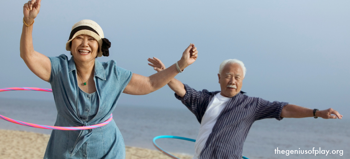 middle aged, Asian-American couple hula hooping outdoors