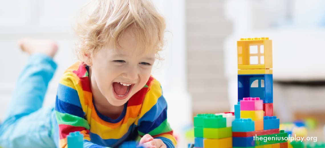 young blond boy playing with colorful toy blocks