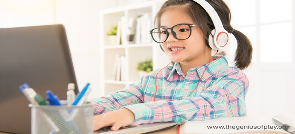 Elementary school age girl wearing headphones typing on computer