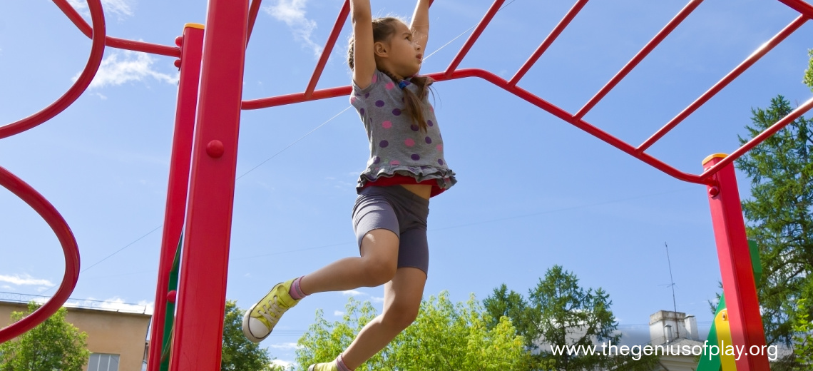 young girl holding onto monkey bars