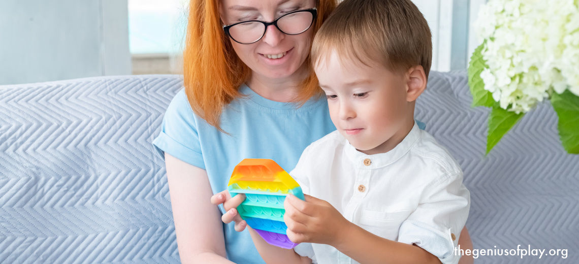 mother and young child playing with fidget toy while sitting on couch waiting for appointment