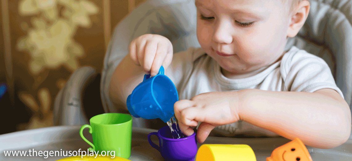 young child pouring water from one cup into another