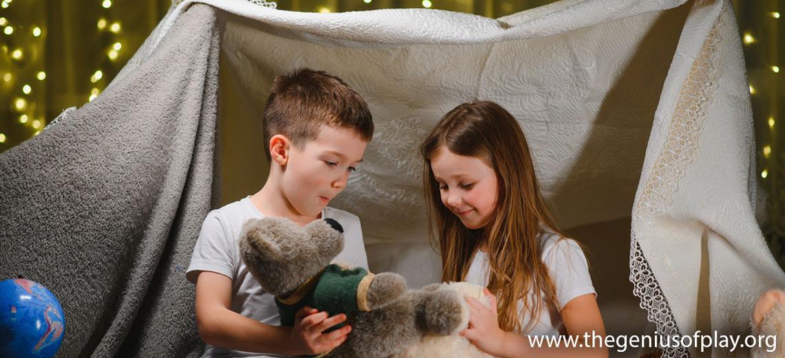 Girl and boy playing in indoor bedroom fort